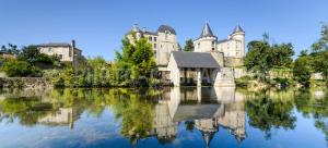 um castelo refletido na água de um lago em La Tuilerie em Verteuil-sur-Charente