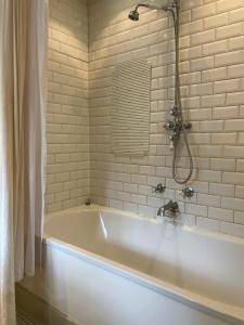 a white bath tub in a bathroom with a shower at Quirky 18th Century Thatched Cottage in Great Staughton