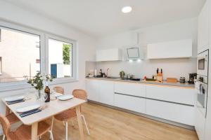 eine Küche mit weißen Schränken und einem Tisch mit Stühlen in der Unterkunft Moderne & Elegante Terrassenwohnung - Wifi - TV in Bielefeld