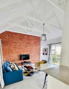 a living room with a brick wall and a blue couch at Stylish Loft Style Apartment in Durban