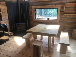 a wooden table and bench in a room with a window at Mini Moo-light Cabin in Clearwater