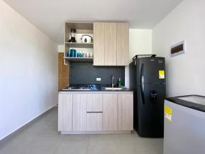 a kitchen with a black refrigerator and a stove at NAHIR apartamento de playa en condominio Palmar del viento in San Bernardo del Viento