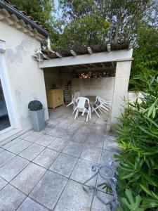 een patio met stoelen, een tafel en een dak bij Maison climatisée, 3 chambres, 2 étoiles, tout confort in Noves