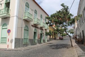 a street with a building with green windows and a tree at Djarfogo house in São Filipe