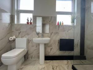 a bathroom with a white toilet and a sink at Sleek & Stylish Spacious Apartment near Leeds City Centre in Headingley