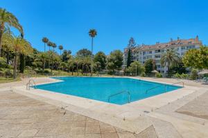 a swimming pool in a park with palm trees and a building at Torre Real Vistas 360 cerca Trocadero Arena Marbella in Marbella