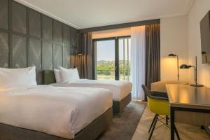 a hotel room with two beds and a desk at Four Points by Sheraton Budapest Danube in Budapest