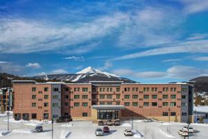 ein großes Backsteingebäude mit einem schneebedeckten Berg im Hintergrund in der Unterkunft Residence Inn by Marriott Big Sky/The Wilson Hotel in Big Sky