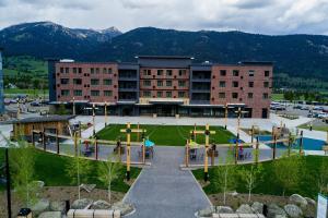 un bâtiment avec une aire de jeux avec des montagnes en arrière-plan dans l'établissement Residence Inn by Marriott Big Sky/The Wilson Hotel, à Big Sky