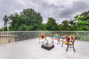a patio with two chairs and a table and a fence at SaffronStays Amrapali - 5BHK Villa in Nashik with Pool, Lawn & Kids Play Area in Deolāli