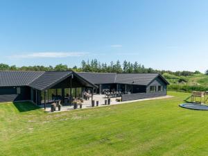 un gran edificio con un campo de césped delante de él en 26 person holiday home in Nørre Nebel, en Nørre Nebel