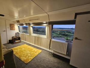 a train room with two windows and a yellow rug at Mooview- the charming double decker bus in Norton