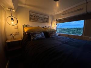 a bedroom with a large bed with a window at Mooview- the charming double decker bus in Norton