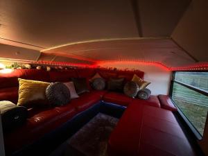 a living room with a red couch with pillows at Mooview- the charming double decker bus in Norton +16 photos
