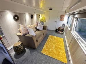 - un salon avec un canapé et un tapis jaune dans l'établissement Mooview- the charming double decker bus, à Norton