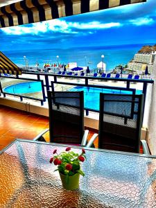 een glazen tafel met een vaas met bloemen op een balkon bij apartmant Adrian Vista Taurito in Taurito