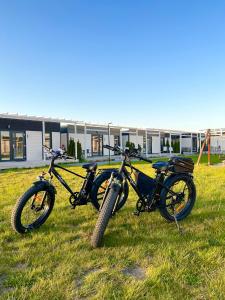 deux motocycles garés sur l'herbe devant un bâtiment dans l'établissement Resto domki letniskowe, à Sarbinowo