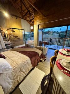 1 Schlafzimmer mit einem Bett und einem Balkon mit einem Tisch in der Unterkunft CHALES CAMBARA DA SERRA in São José dos Pinhais