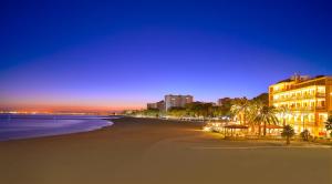 - une plage de nuit avec des bâtiments et des palmiers dans l'établissement Hostal La Torre, à Benicàssim