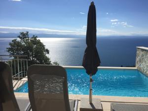 ein Sonnenschirm und Stühle neben einem Pool in der Unterkunft Villa Sabine Apartment Cres in Medveja