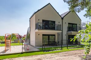 a house with a playground in front of it at Apartamenty w sam las by KLIF Ustka - apartament dwupoziomy z klimatyzacją i widokiem na las in Ustka