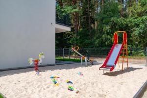 a playground with a slide and play equipment in the sand at Apartamenty w sam las by KLIF Ustka - apartament dwupoziomy z klimatyzacją i widokiem na las in Ustka