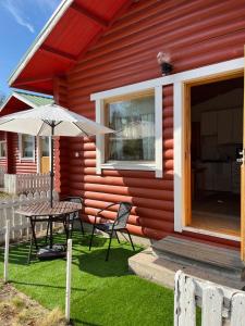 a red house with a table and an umbrella at Lapland Arctic Cabins 