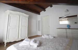 a white bedroom with a large bed and a dresser at La Casa di Filippo in Palermo