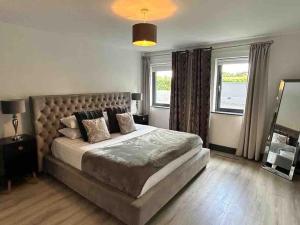 a bedroom with a large bed and two windows at Killarney modern family cottage in Killarney