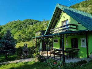 una casa verde con mesa y bancos al aire libre en Private beach holiday home Ilan, en Kulen Vakuf