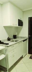 a white kitchen with a sink and a microwave at Quarto Jaraguá/São Luís in Jaraguá do Sul