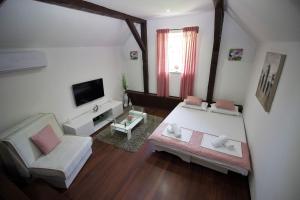 a living room with a white bed and a tv at Vila Zahumka Free Parking in Mostar
