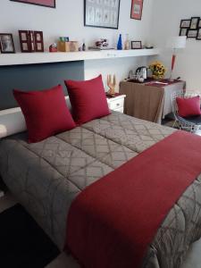 um quarto com uma cama grande e almofadas vermelhas em B&B - El Refugio -C D em Paraná