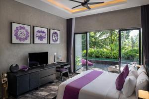 Capung Asri Eco Luxury Resort with Private Pool Villas في Bedahulu: غرفة نوم بسرير ومكتب وتلفزيون
