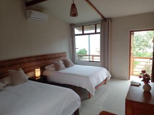 um quarto com 2 camas e uma grande janela em Entre Palmeras em Bocapán