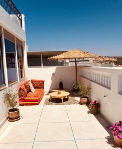 patio con divano, tavolo e ombrellone di cactus surf house a Tamraght Ouzdar