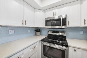 a kitchen with white cabinets and a stove and microwave at 6415 Midnight Pass #608 in Siesta Key