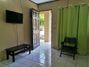 a living room with a tv and a chair and a door at HOTEL Apartamentos Herradura #5 Familiar in Herradura