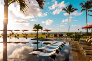 una piscina en un complejo con palmeras y el océano en Sheraton Kauai Coconut Beach Resort en Kapaa