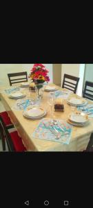 a table with plates and glasses and a vase of flowers at Villa tolis in Mádhena