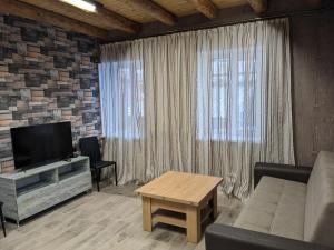 a living room with a couch and a tv and a table at Sundukyan Apartments in Gyumri