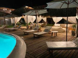 a deck with chairs and umbrellas and a swimming pool at Entre Palmeras in Bocapán