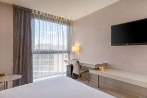 um quarto de hotel com uma cama, uma secretária e uma janela em AC Hotel San Cugat by Marriott em Sant Cugat del Vallès