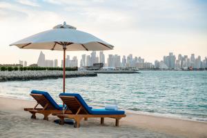 ドーハにあるSharq Village & Spa, a Ritz-Carlton Hotelのビーチでの椅子2脚とパラソル1本