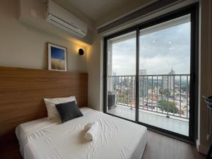 1 dormitorio con cama y ventana grande en Houx Pinheiros en São Paulo
