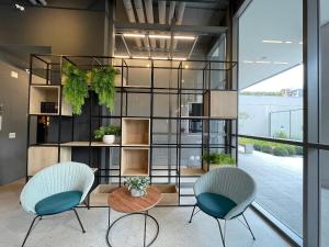 una habitación con 2 sillas y un estante con plantas en Houx Pinheiros en São Paulo