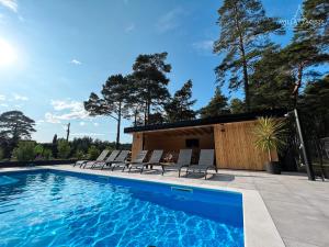 a swimming pool with chairs and a house at Willa Zacisze - Ostrowo - Komfortowe Apartamenty i Pokoje w cichej okolicy - Oaza spokoju in Ostrowo