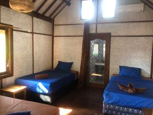 Habitación con 2 camas con sábanas azules y espejo. en La Bohème, en Gili Air