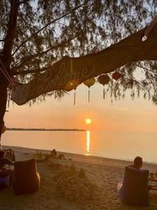 a group of people sitting on the beach watching the sunset at La Bohème in Gili Air