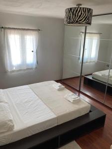 a bedroom with a white bed and a mirror at V&V Pink House in San Mauro
